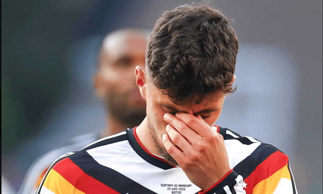 A close-up of a disappointed German football player looking down with his hand covering his eyes. Paraguay vs Germany